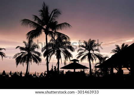 Silhouette of palm trees and beach huts in Thailand