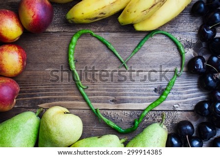 heart shape -fresh grouped healthy green peppers on dark wooden - massive grouped fruits background