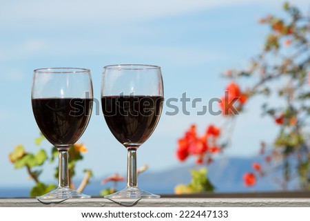 Two glasses of wine on a background of blue sky. Red wine poured into a wine glass on a background of mountain scenery. Two glasses of red wine in a romantic atmosphere.