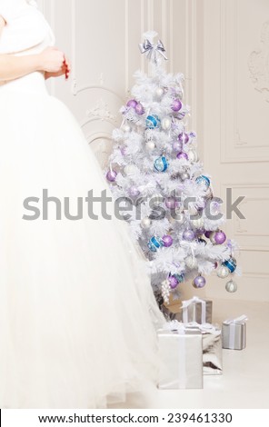Christmas tree decorated with toys, holiday gifts. The female body is blurred, close to the beautiful a silver Christmas tree. New Year, decoration holiday concept where there are gifts.