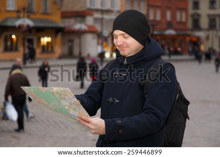 A man traveling in Europe. A man with a map in the main square of Warsaw, near the palace. Man on vacation travels.