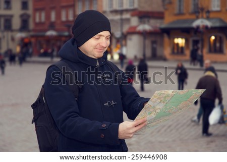A man traveling in Europe. A man with a map in the main square of Warsaw, near the palace. Man on vacation travels.