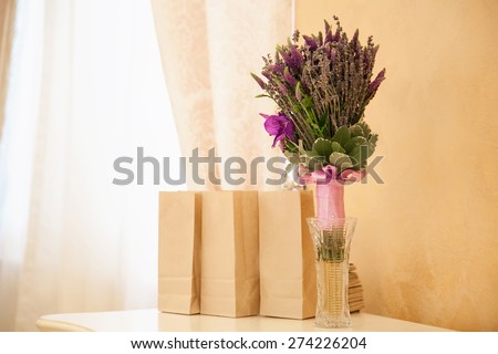 Kraft bags with gifts and wedding bouquet on a table stand. Paper eco bags for food in the restaurant.A row of brown paper bags with a flower bouquet on the table.