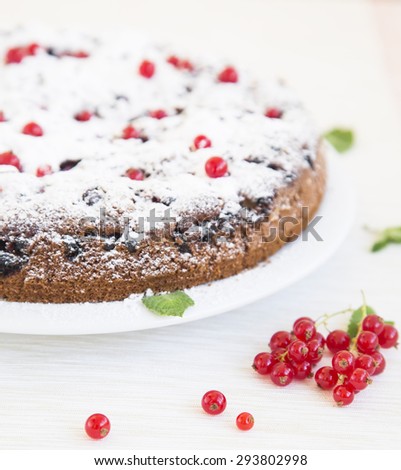 Honey cake filled with red currant. Baking with currants on a light background. Baked products, currants, mint, powdered sugar in a composition about a cake. Advertising of confectionery production.