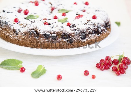 Honey cake filled with red currant. Baking with currants on a light background. Baked products, currants, mint, powdered sugar in a composition about a cake. Advertising of confectionery production.