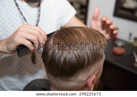 Men\'s hairstyling and haircutting with hair clipper in a barber shop or hair salon. Bearded brutal man in a barber shop.