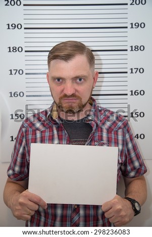 Portrait of a man with a beard on the background grid to measure growth. Man holds a plate for inscriptions. Happy adult man with a beard and mustache, smiling and looking at the camera. Wanted