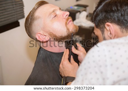 Grooming the beard. Barbershop. Man hairdresser doing haircut beard adult men in the men's hair salon. Hairdressers in the workplace. Barber. Grooming the beard. Barbershop.