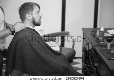 Men\'s hairstyling and haircutting with hair clipper in a barber shop or hair salon. Bearded brutal man in a barber shop. black and white image