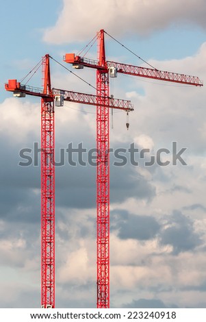 Two red crane on the sky background. Two red construction crane on the sky with clouds background