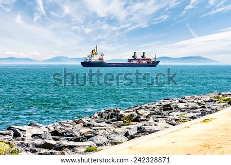 Cargo ship sails on a background of blue mountains. Cargo ship sails along the Bosphorus on a background of blue mountains, blue sky and beautiful clouds.