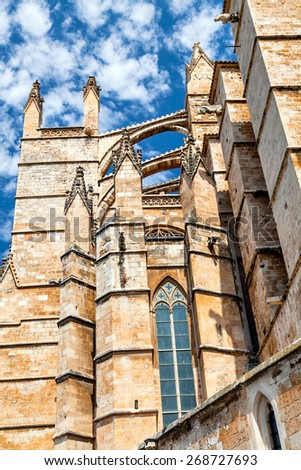 Wall Gothic cathedral in Palma de Mallorca on the sky background. Bottom view on a Gothic cathedral on the sky background in Palma de Mallorca in the summer sunny day. Gothic stained glass, arches.