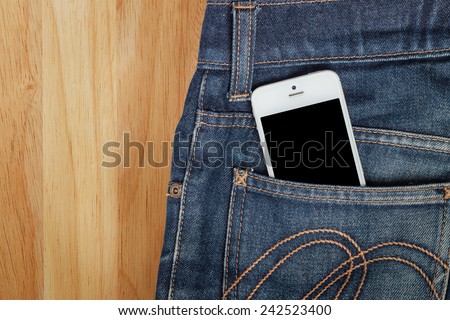 Smart phone in jeans pocket on wood