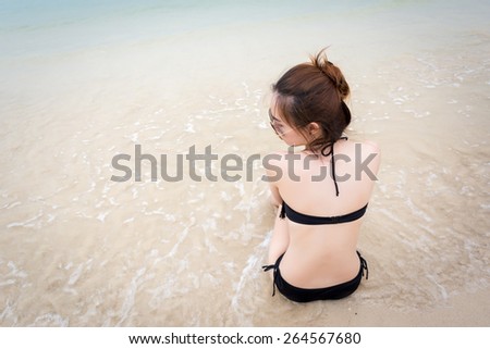 Beautiful Asian woman sitting on the beach ocean on hot summer day. Photo from beach