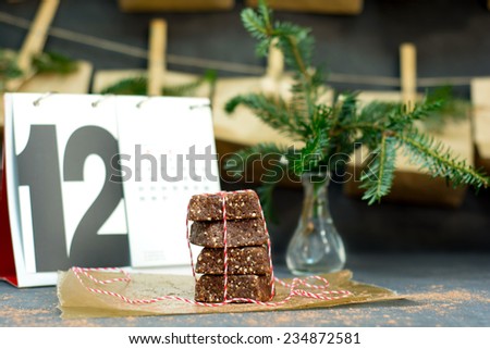 Home made coco date pecan nutrition bars wrapped with a red and white ribbon with a calendar and Advent calendar in the background