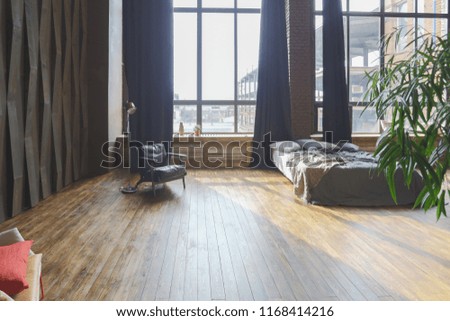 Large spacious loft room in dark colors in the rays of sunlight with big window. free lay-out