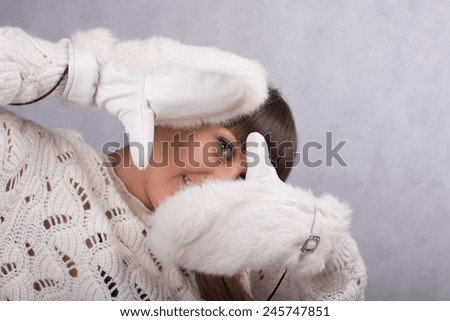 beautiful young brunette woman in white warm sweater and white fur mittens