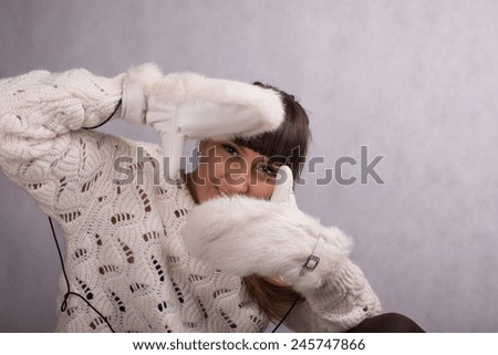 beautiful young brunette woman in white warm sweater and white fur mittens