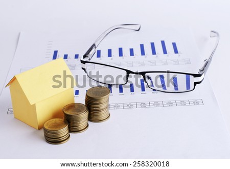 House paper and coins and Eyeglass on chart for Loans money concept