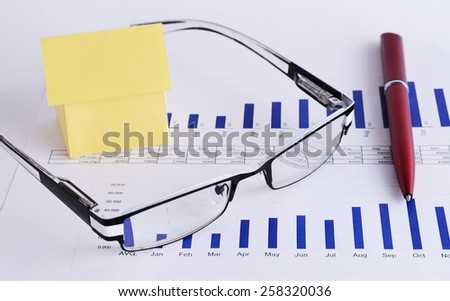 Close up of eyeglass and pen with house paper on chart for Loans money concept
