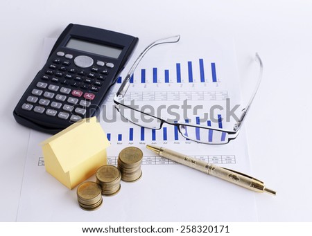 House paper and coins stack with Eyeglass and Calculator and pen on Chart for Loans money concept