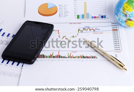 mobile phone and pen on stock market chart for finance concept