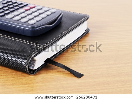 Close up of Calculator and Business old book on wooden desk for Business Concept