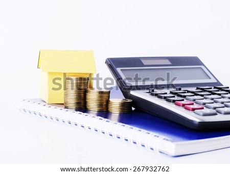 Money coins stack and paper house and Calculator on Blue diary book for Loans concept
