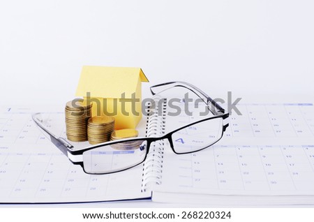 Loans concept with Eyeglasses and money coins stack and paper house on Calendar book pages