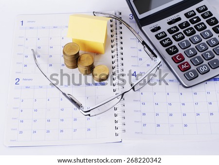 mortgage loans concept with Eyeglasses and coins stack and paper house and calculator on Calendar book pages