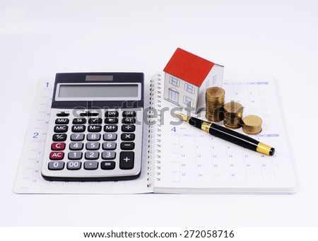 Home loans concept with Calculator and Fountain pen and paper house and money coins stack on calendar book pages