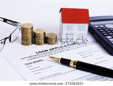 Business fountain pen and loan application form and calculator and paper house and coins stack and eyeglasses for mortgage loans concept
