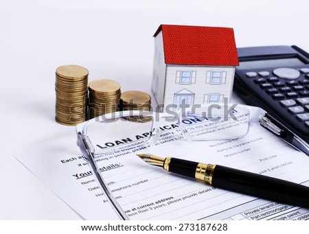 Mortgage Loans concept with close up Business Fountain pen on Loan application form and eyeglasses and coins stack and paper house