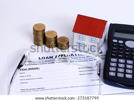 Mortgage Loans concept with close up Loan application form and eyeglasses and coins stack and paper house and calculator