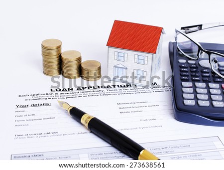 Loans application form and fountain pen and paper house and coins stack and eyeglasses on calculator