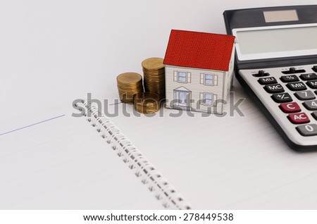 Home loans concept with paper house and coins stack and calculate on book pages