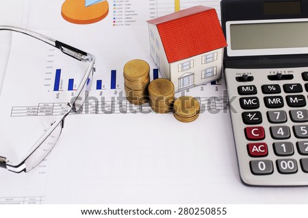 Home loans concept with close up coins stack and paper house and calculator and eyeglasses