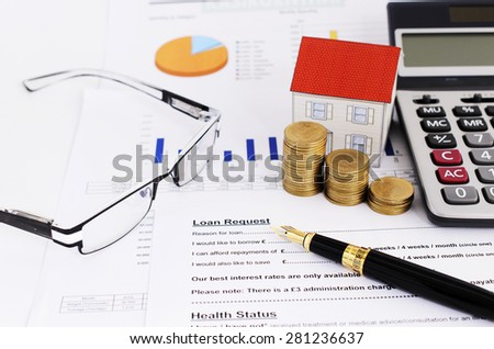 Mortgage loans concept with close up or Fountain pen and coins stack and paper house and calculator and glasses on loans request form