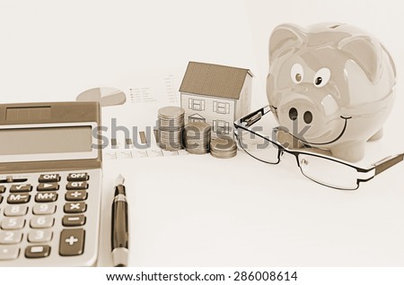 Sepia style for Saving money plan with piggy bank and paper house and eyeglasses and calculator and fountain pen