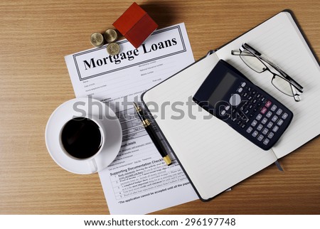 Mortgage loans concept with house paper and coins stack and coffee cup and fountain pen and calculator and eyeglasses on worktable with document
