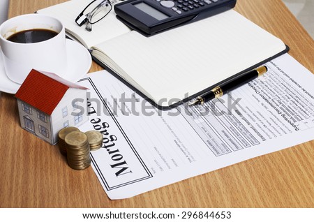 House paper with coins stack on mortgage application form on worktable