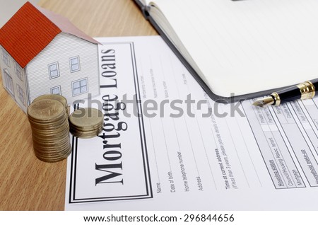 Close up of coins stack with house paper and mortgage loans application form