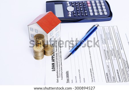 Blue pen with coins stack and house paper and calculator on loans application for Mortgage loan concept