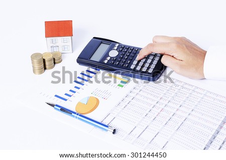 Calculator and pen on business chart with coins stack and house paper for home loan concept