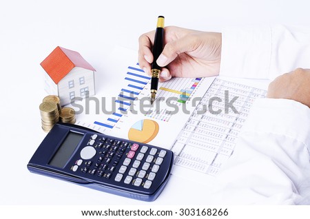 close up of business fountain pen on chart with house paper, coins stack and calculator for Mortgage loans concept