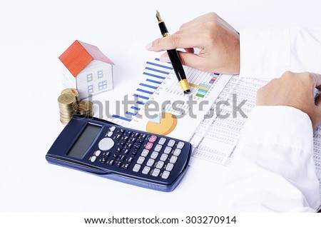 close up of House paper with coins stack with calculator and hand holding fountain pen on chart for Mortgage loans concept