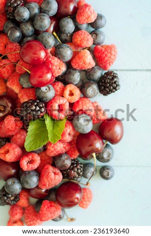 Delicious fresh berries on blue wooden background