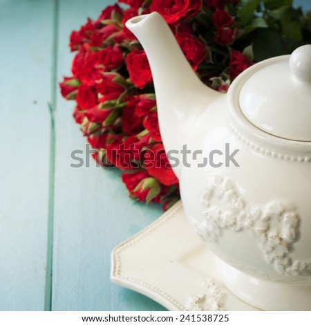 tea kettle and a bouquet of red roses