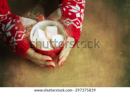 Hands holding a mug of hot chocolate with marshmallows