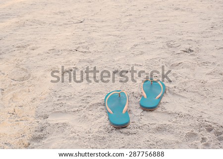 Summer vacation concept. Flip flops on a sandy ocean beach in vintage tone color style, selective focus (detailed close-up shot)